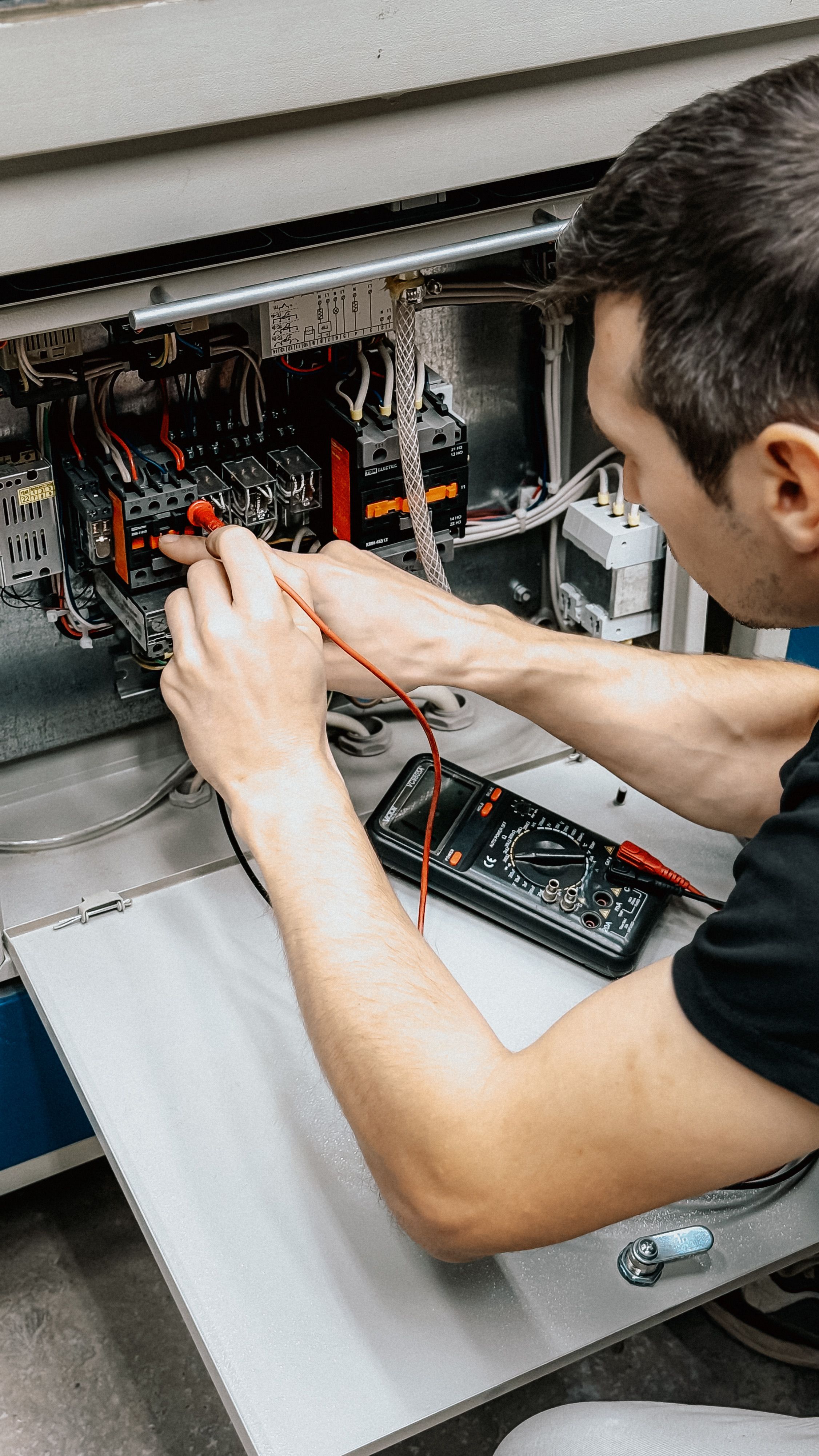 Electrician working on a consumer unit with a multimeter